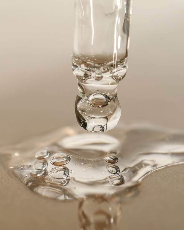 Close-up of a water droplet falling onto a reflective surface with a blurred background